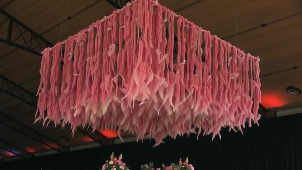 Instalação floral rosa suspensa sobre salão de festas decorado